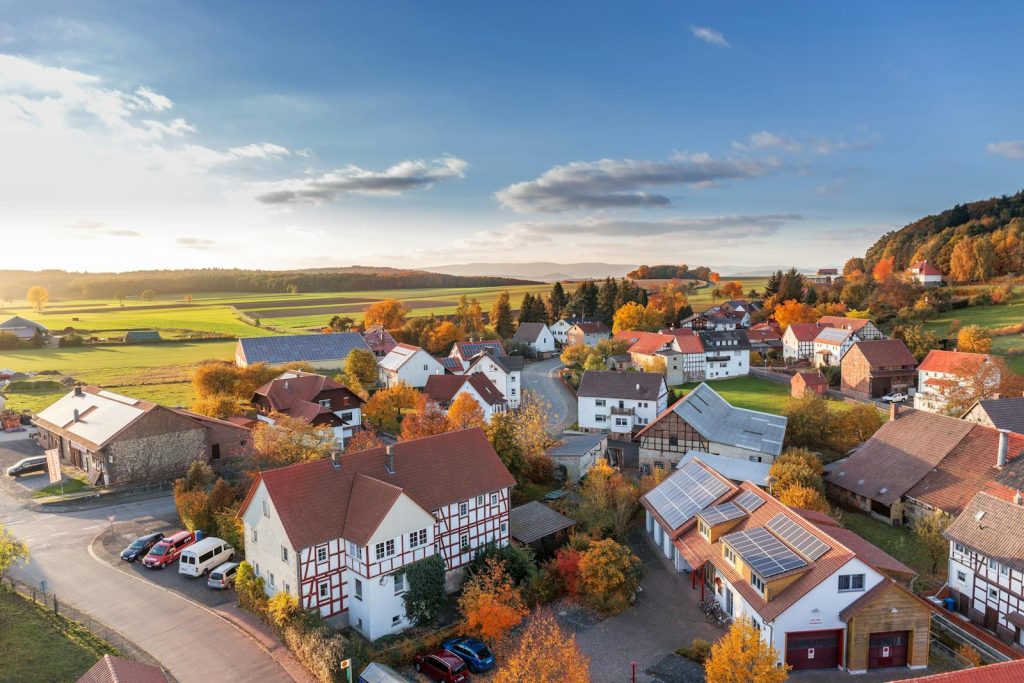 Vue aérienne charmante d'un village rural en automne avec des couleurs vives et un ciel dégagé.